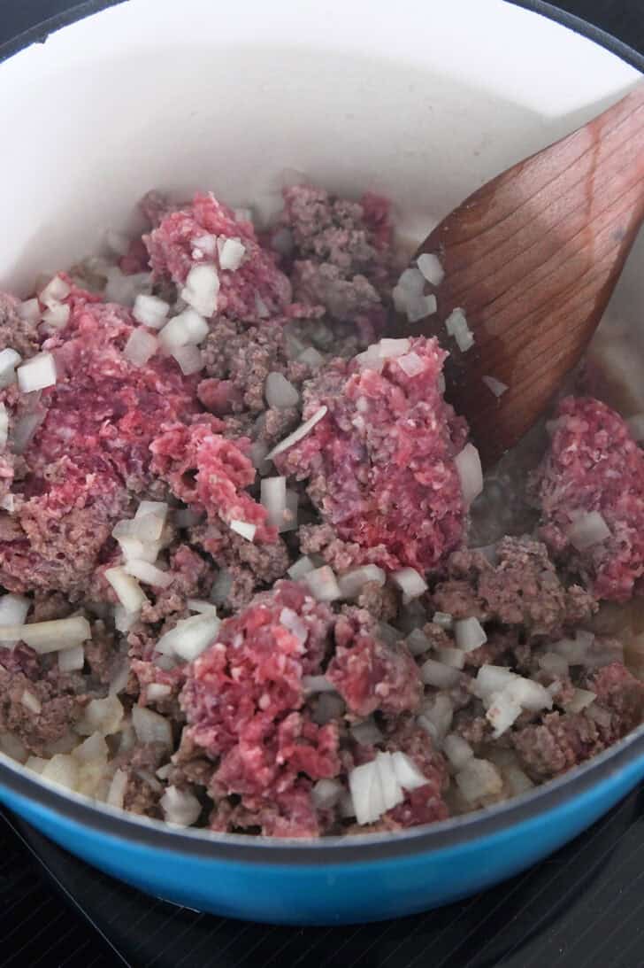 Dutch oven with ground beef, onions, and garlic.