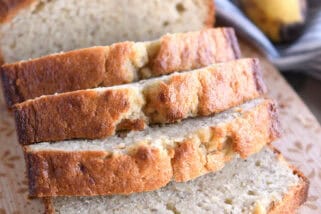 Four slices of buttermilk banana bread on wood cutting board.
