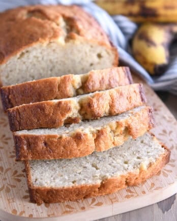 Four slices of buttermilk banana bread on wood cutting board.