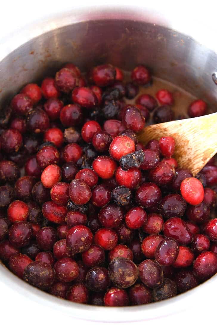 Saucepan with cranberries, cinnamon and sugar.