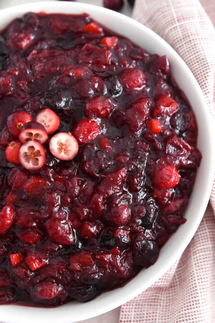 Top down view of thick cranberry chutney in white bowl.