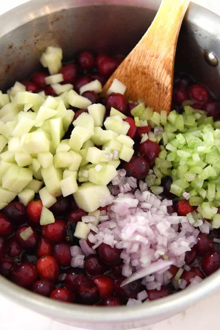 Saucepan with cooked cranberries, celery, green apples and shallots.