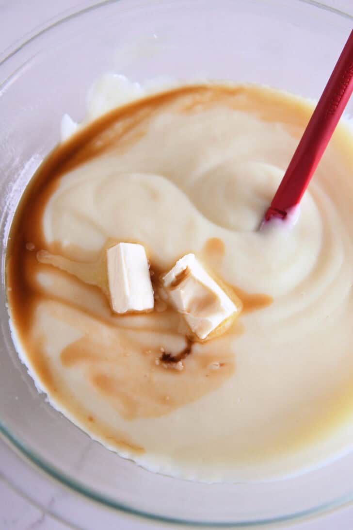 Cooked pudding with butter and vanilla in glass bowl.