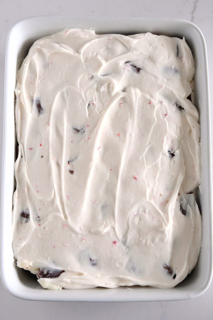 Peppermint cream cheese layer spread over the top of pudding in white baking dish.