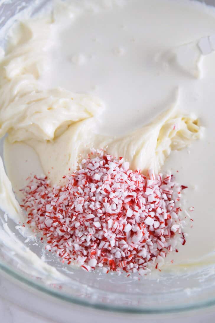 Peppermint pieces in bowl with heavy cream and cream cheese.