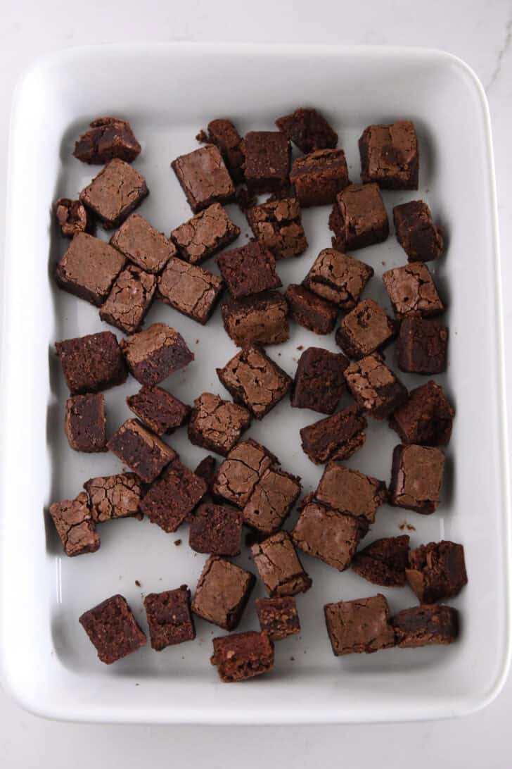 Brownie cubes scattered in bottom of 9X13-inch white dish.