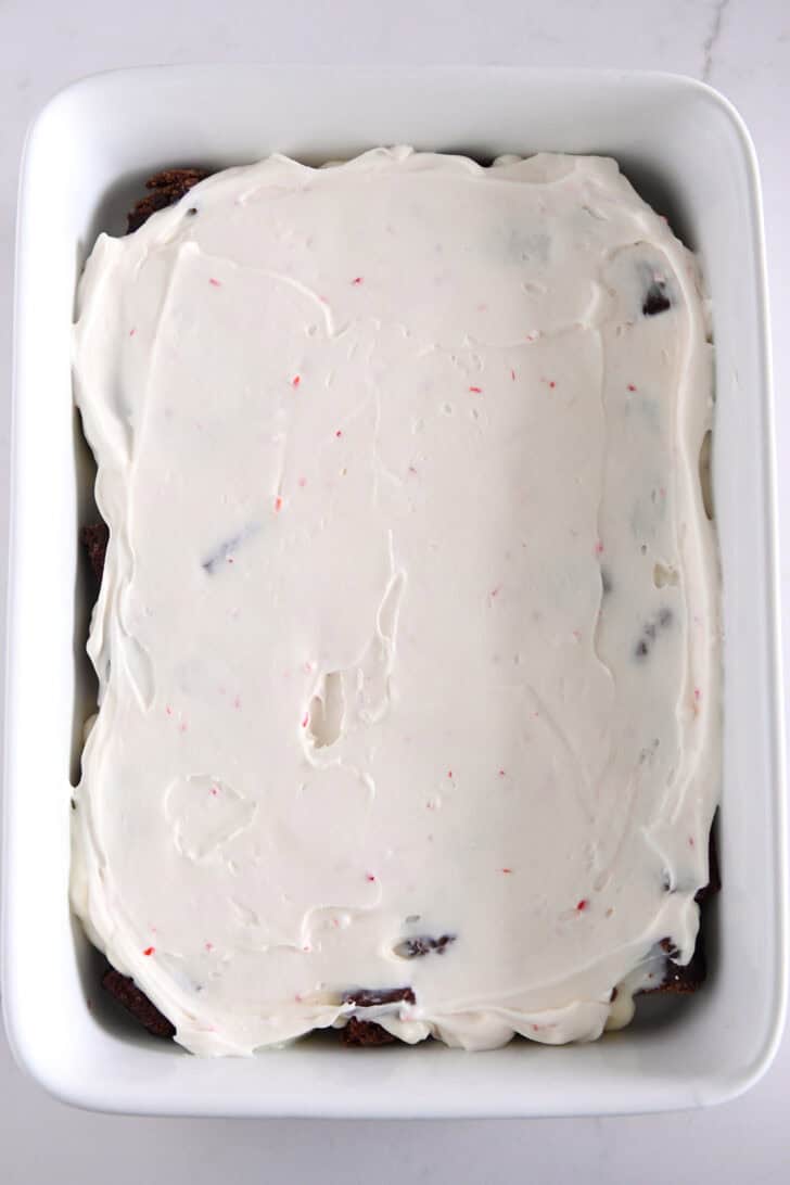 Peppermint cream cheese layer over pudding and brownies in white dish.