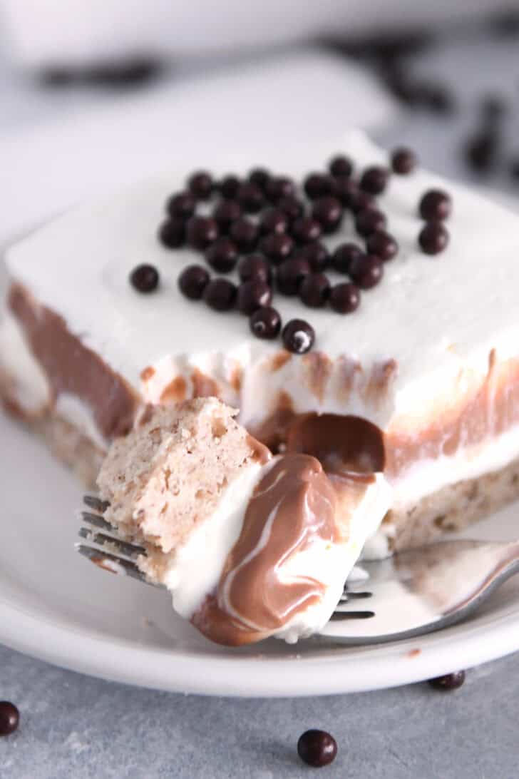 Fork with bite of chocolate pudding dessert on white plate.