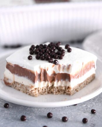 Bite taken out of square of chocolate pudding delight dessert on white plate.