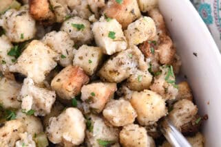 Spoon nestled under baked stuffing in white dish.