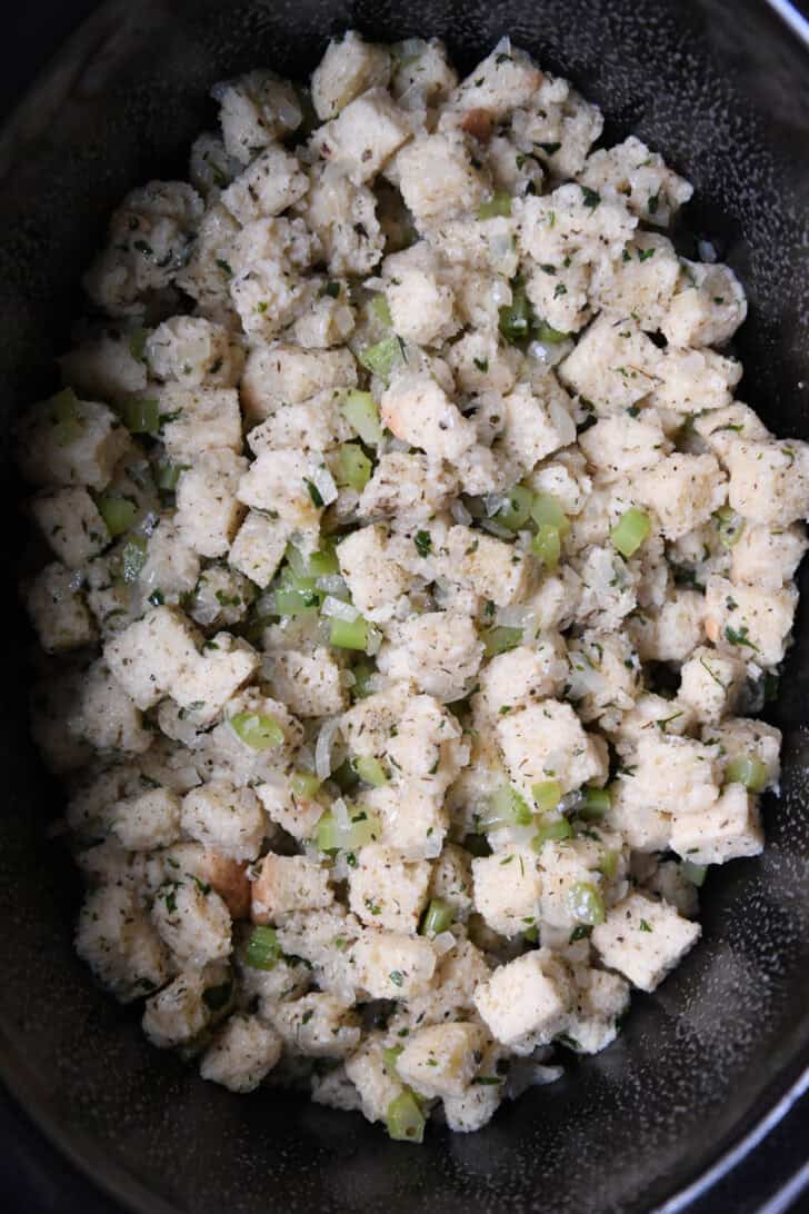 Unbaked stuffing in black oval slow cooker.