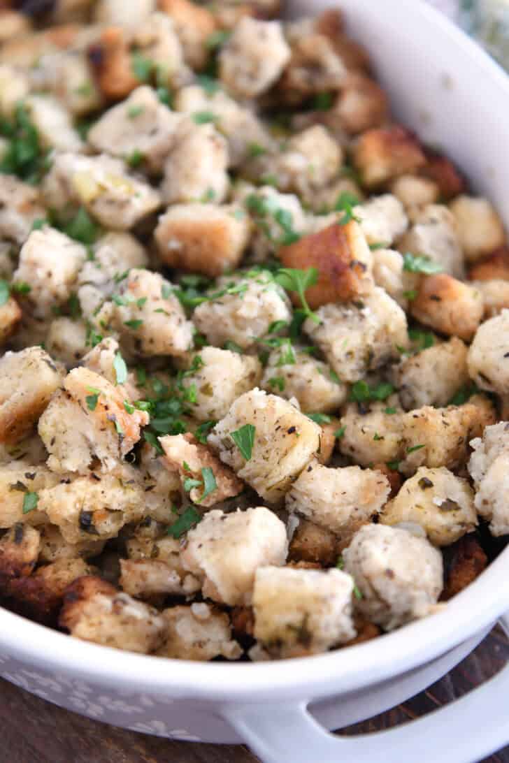 Baked stuffing in white dish topped with fresh parsley.