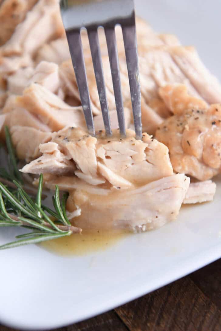 Fork piercing tender piece of slow cooker turkey.