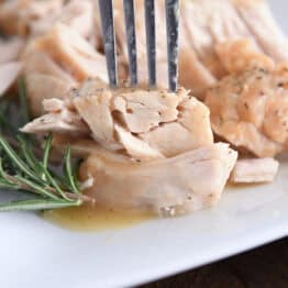 Fork piercing tender piece of slow cooker turkey.