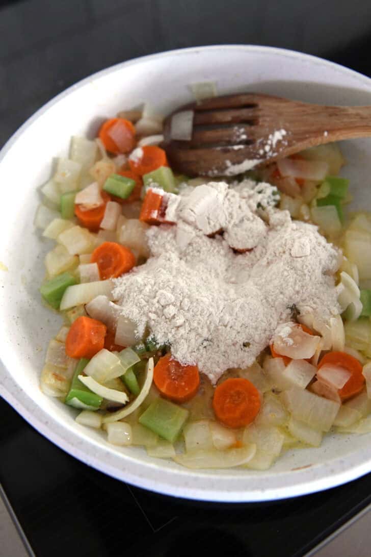 White skillet with flour, carrots, onions and celery.