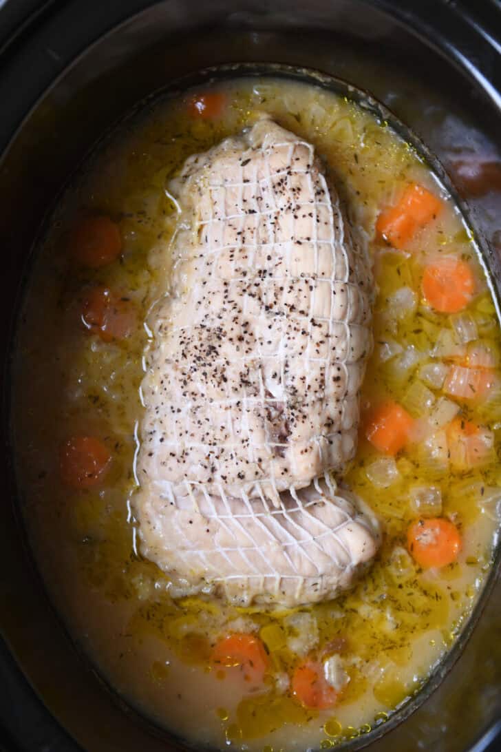 Top down view with cooked turkey breast, carrots, onions and broth.