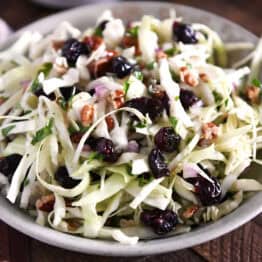 Gray bowl with Thanksgiving slaw with dried cranberries, pecans and red onions.