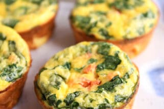 A white platter with golden brown cooked egg and vegetable muffins.