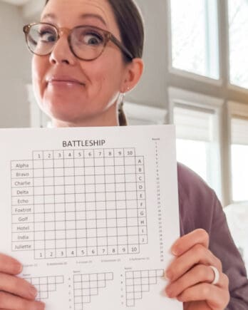 Woman holding paper battleship game.