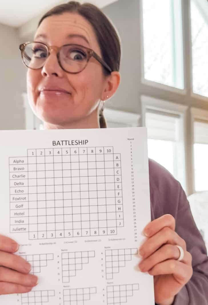 Woman holding paper battleship game.