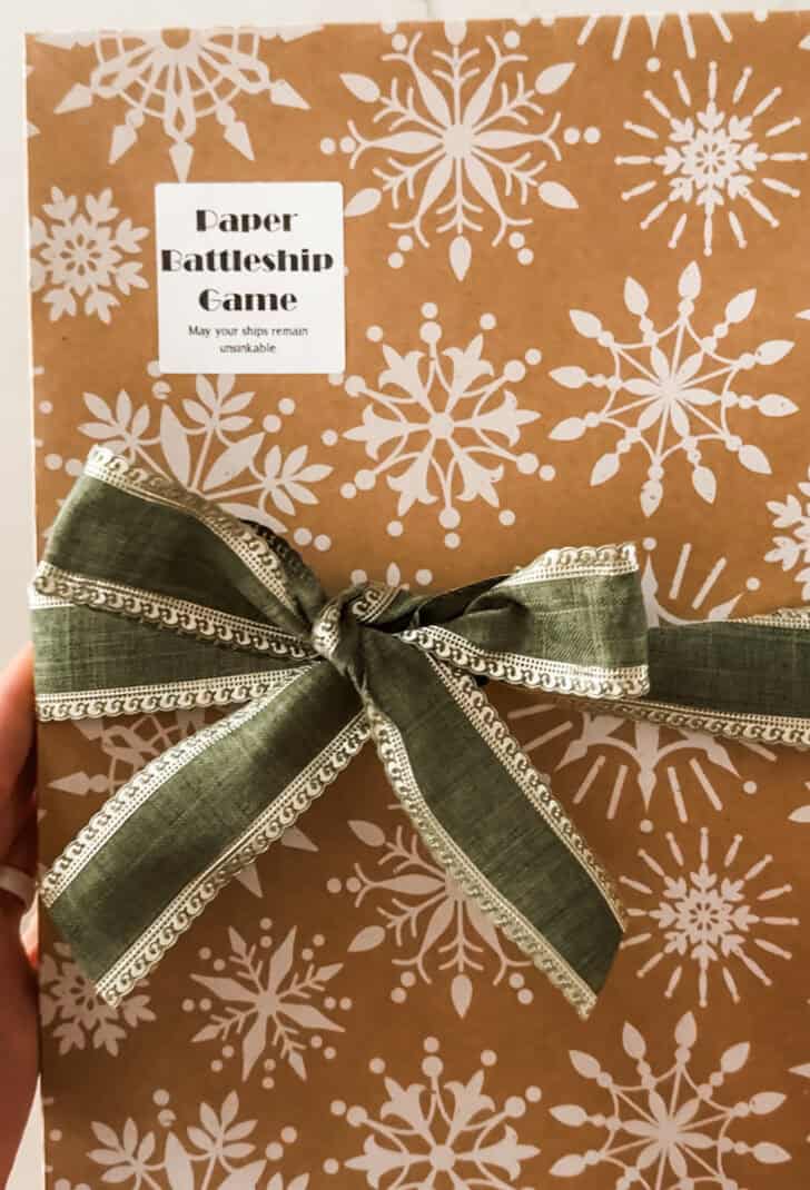 Paper battleship wrapped up in box with a bow.