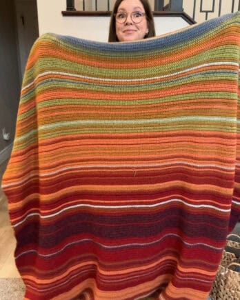 Mel holding crocheted temperature blanket.