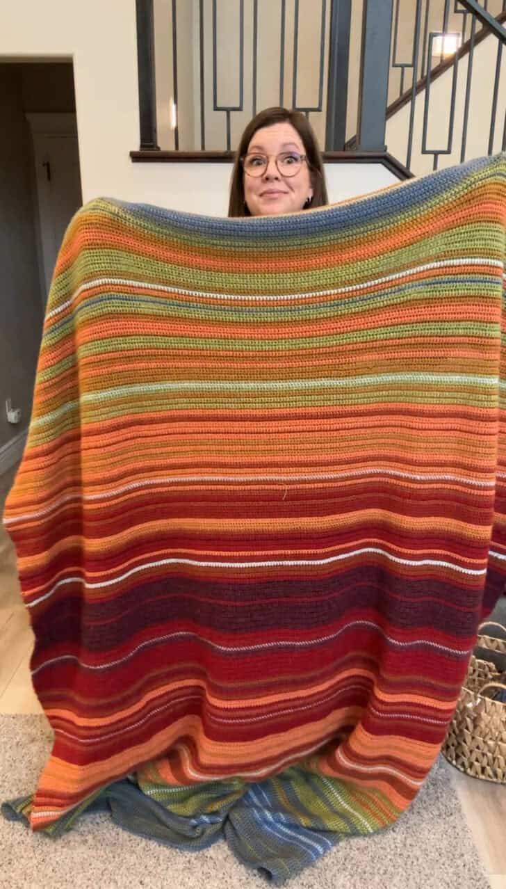 Mel holding crocheted temperature blanket.