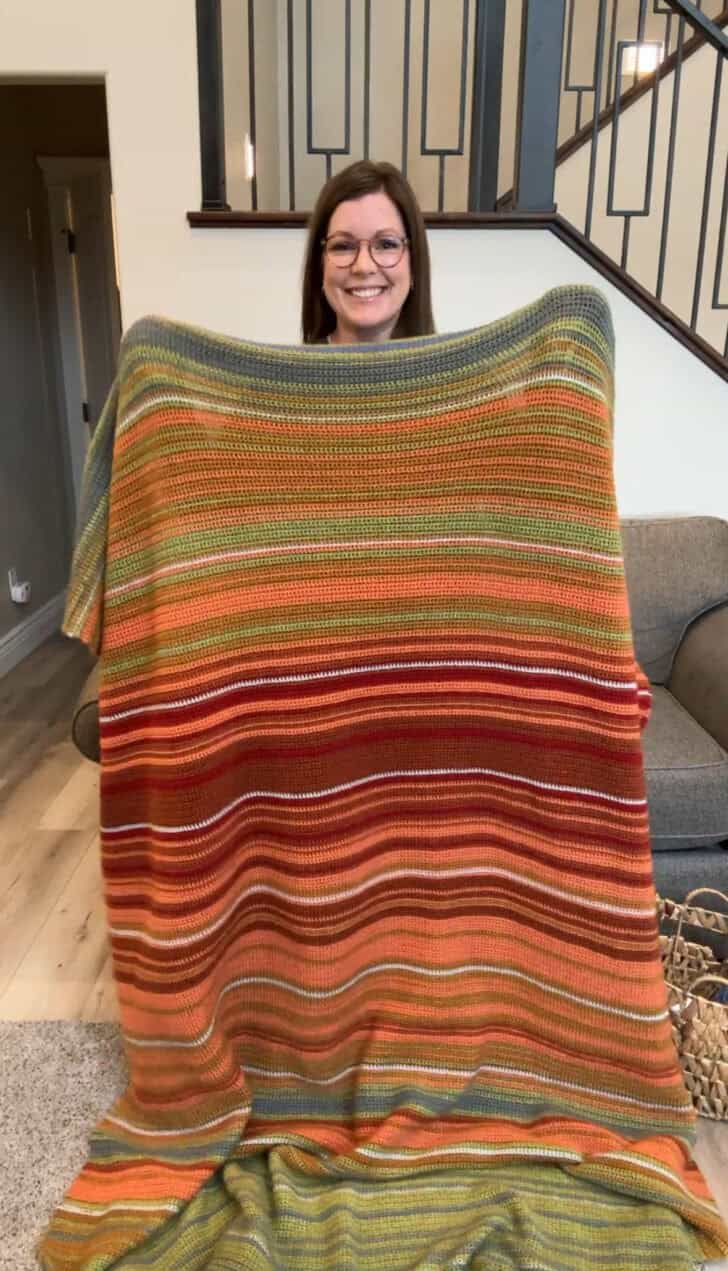 Mel holding crocheted temperature blanket.