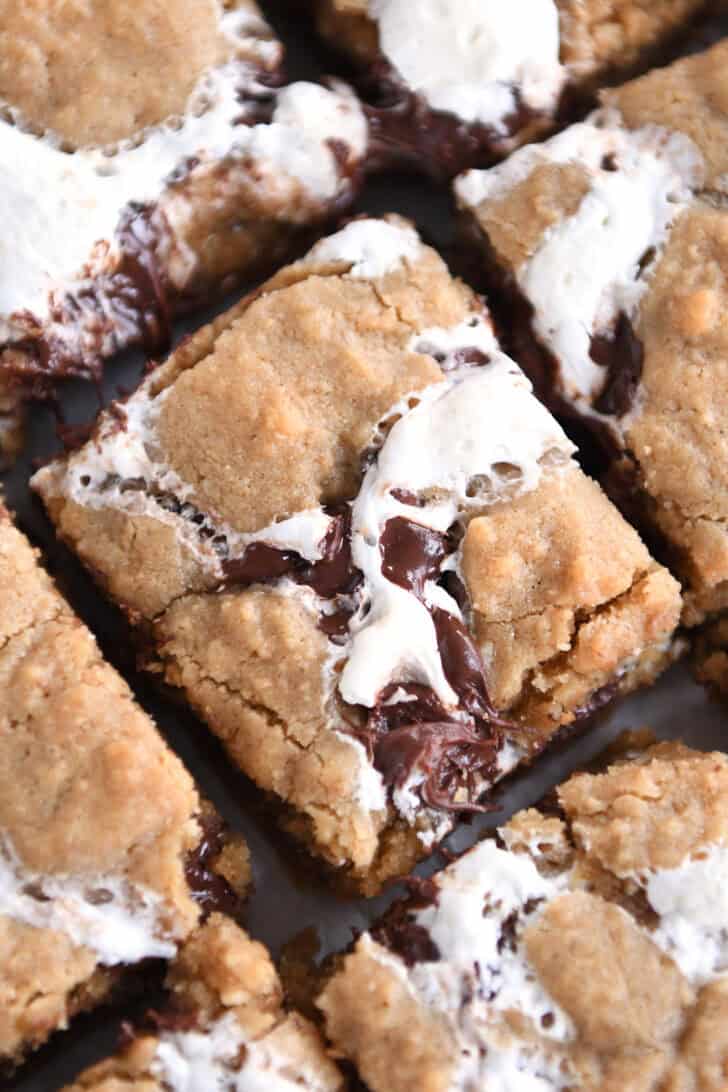 Top down view of golden brown s'mores cookie bars with fissures of gooey marshmallow and melted chocolate throughout each bar.