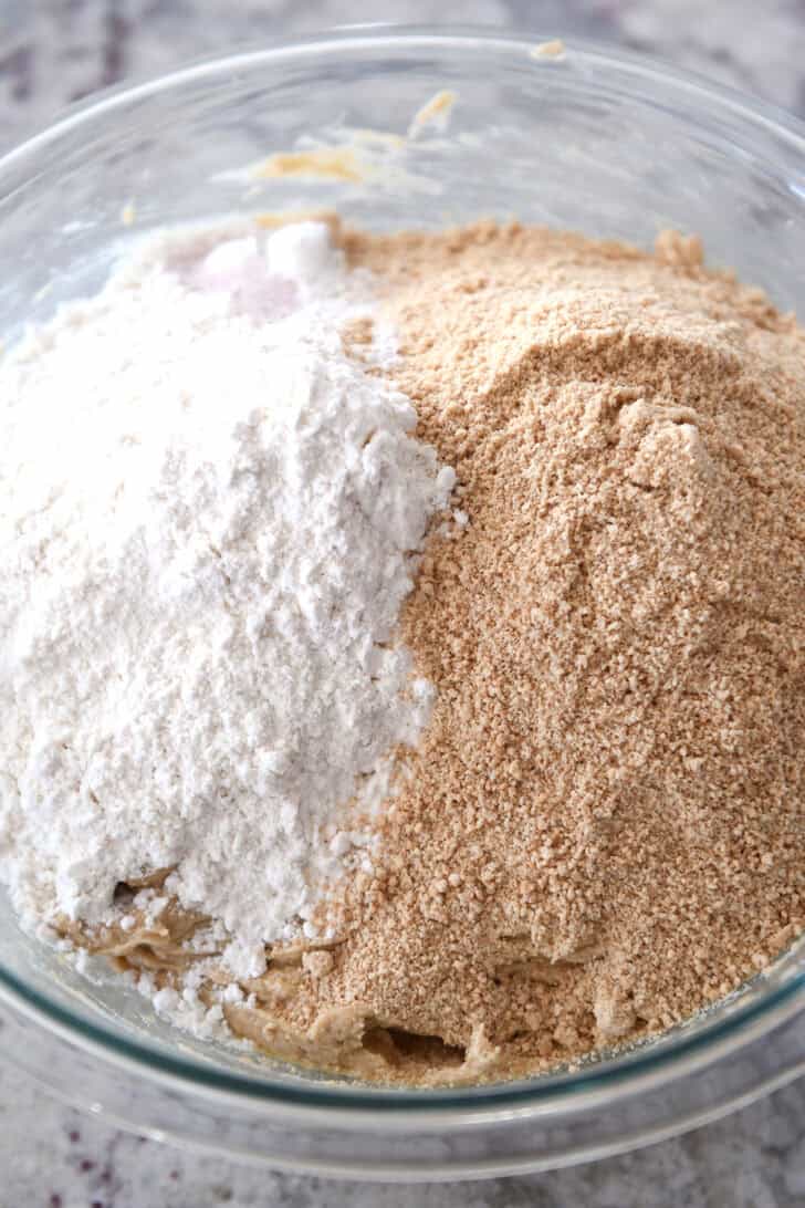 Top down view of a glass bowl filled with flour and graham cracker crumbs.