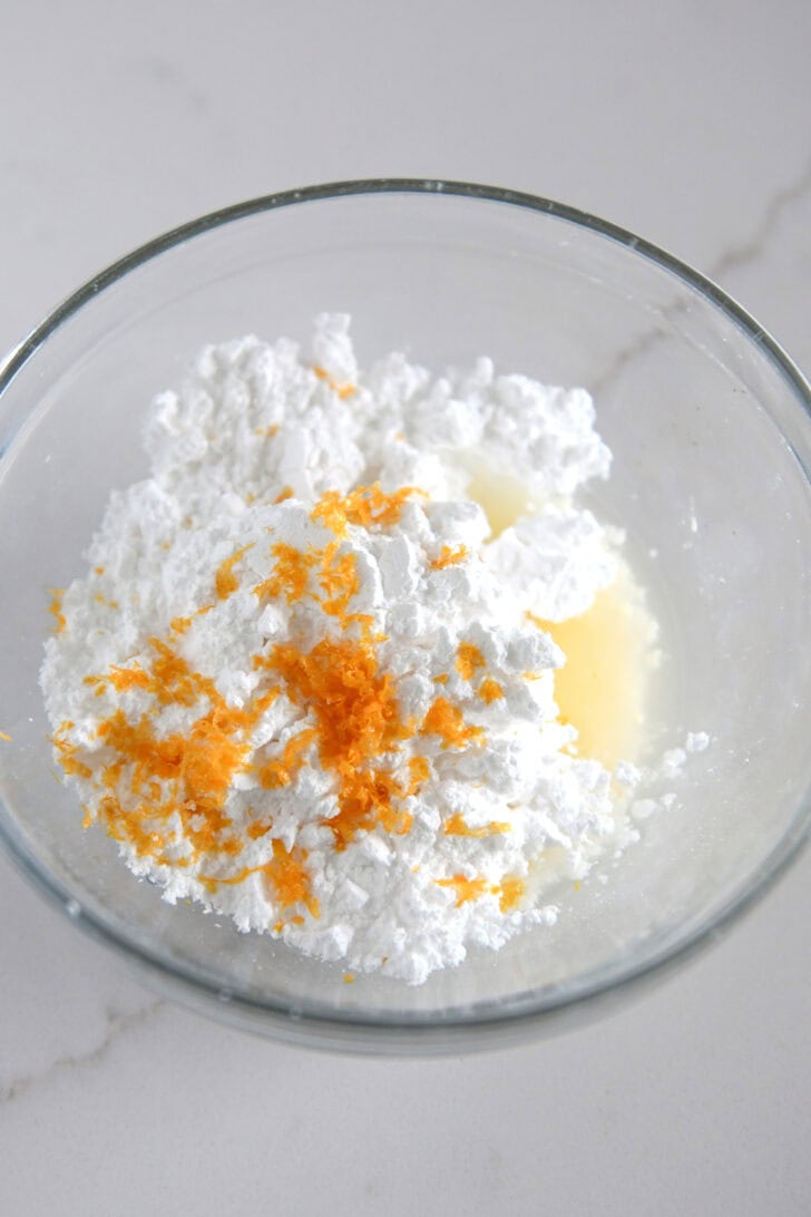 Small bowl with powdered sugar, orange juice and orange zest.