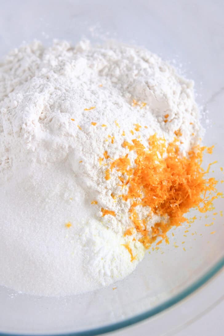 Bowl with fresh orange zest, flour and sugar.