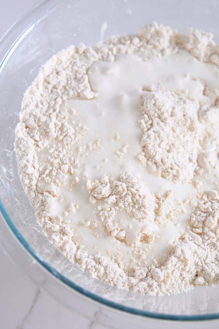 Bowl with flour, small pieces of butter and buttermilk.