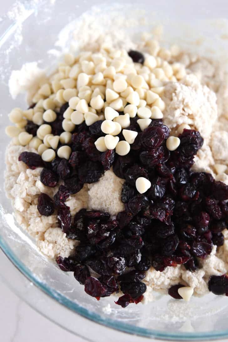 Bowl with scone batter, white chocolate chips and craisins.