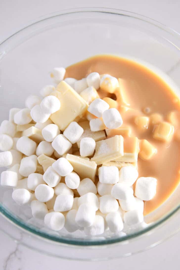 Glass bowl with mini marshmallows, butter, salt and sweetened condensed milk.