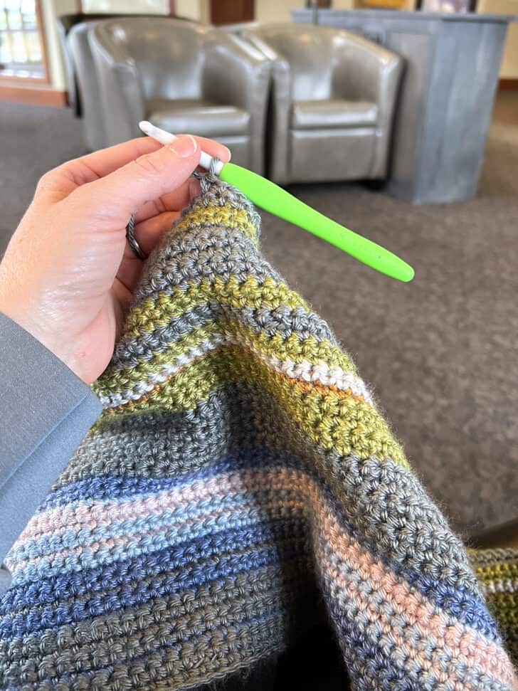 Crocheting gray yarn on temperature blanket in doctor's office.
