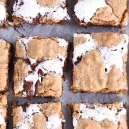 Top down view of golden brown s'mores cookie bars with fissures of gooey marshmallow and melted chocolate throughout each bar.