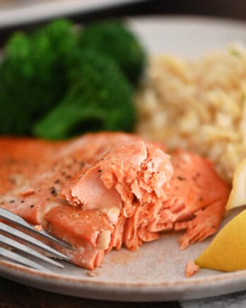 Salmon on gray plate with fork, rice pilaf and cooked broccoli.