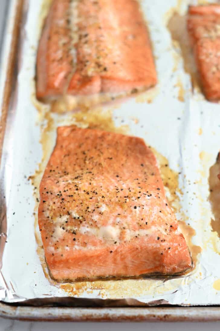 Baked salmon filets on foil-lined baking sheet.