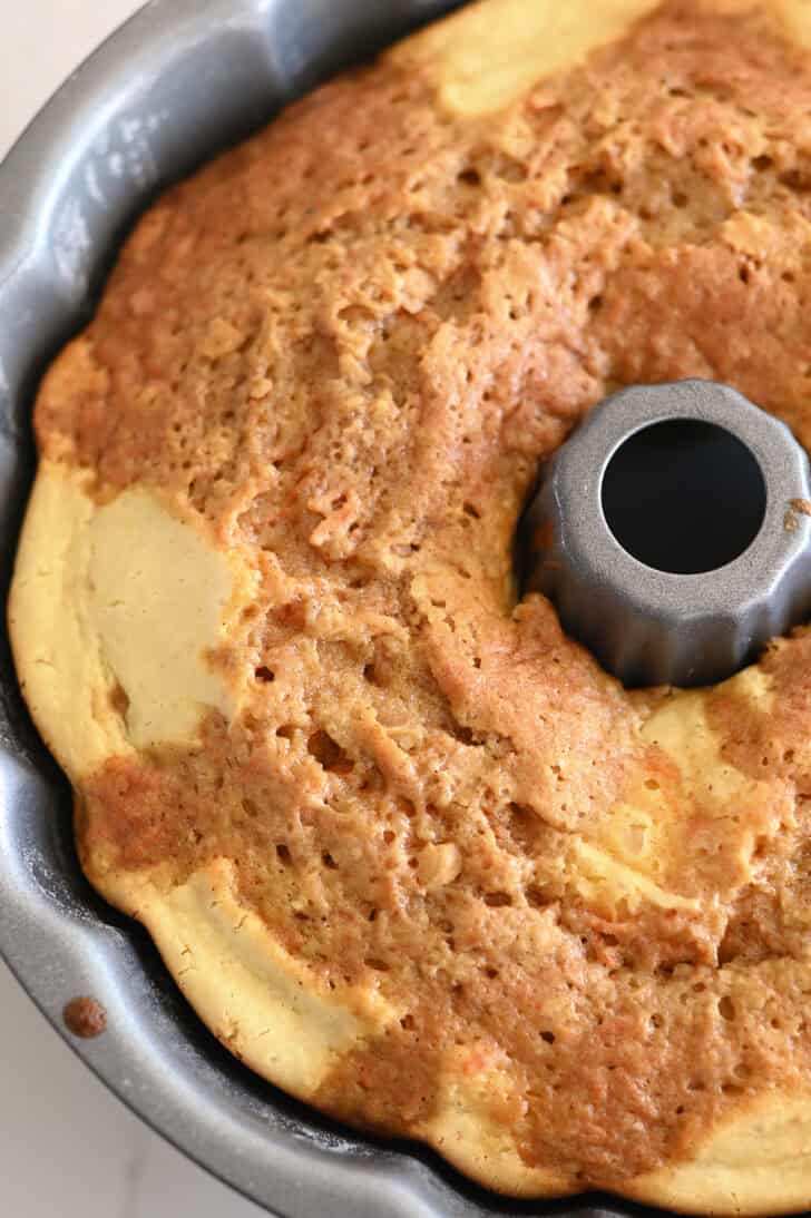 Top down view of a metal bundt pan with a cooked carrot cream chese swirl bundt cake inside.