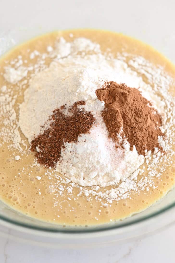 Top down view of carrot cake batter with flour and seasonings on top.