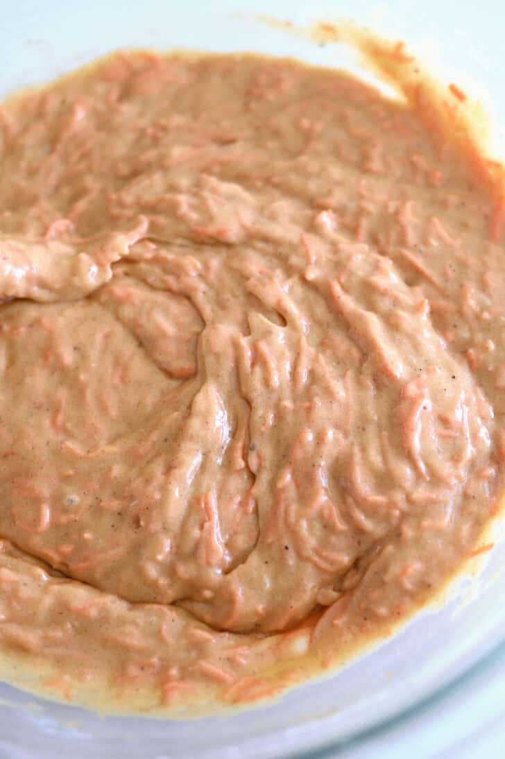 Top down view of a glass bowl filled with raw carrot cake batter.