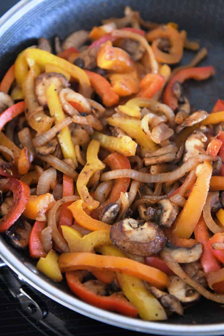 Skillet with sautéed bell peppers, onions, and mushrooms.
