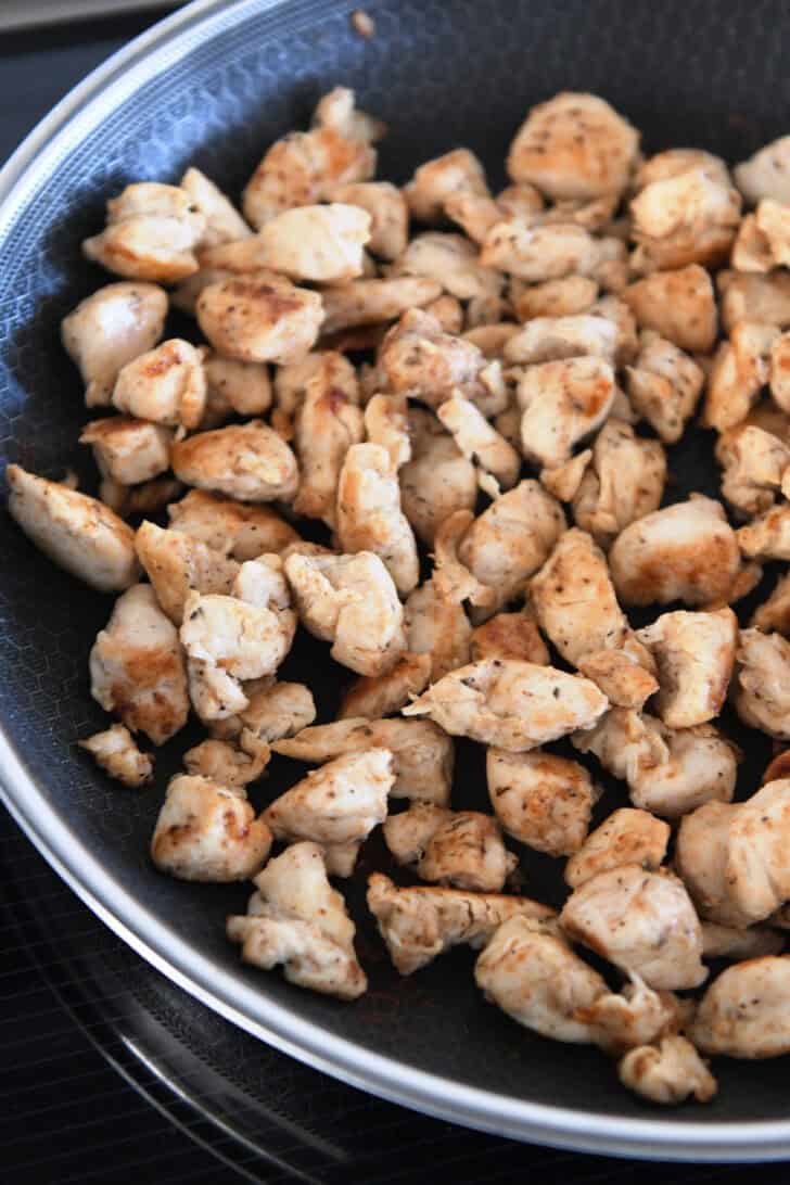 Skillet with golden cooked chicken pieces.