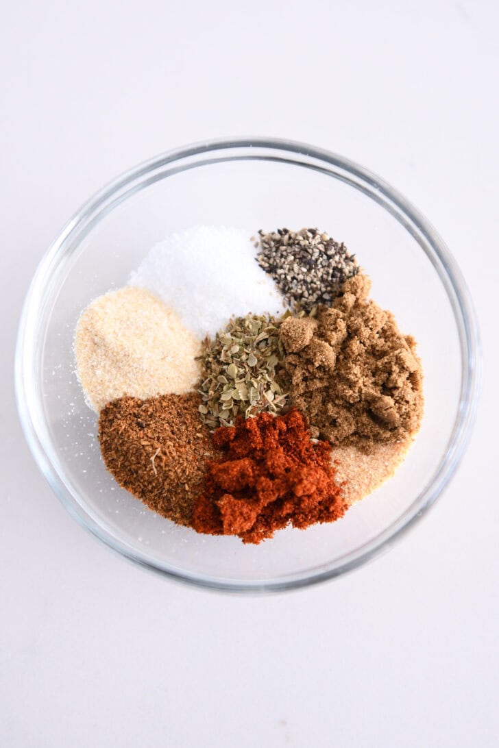 Top down view of bowl with garlic powder, chili powder, paprika, oregano, cumin, salt, pepper and onion powder.