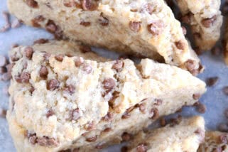 Top view of baked cinnamon chip scones with cinnamon chips sprinkled all around them on a piece of parchment.