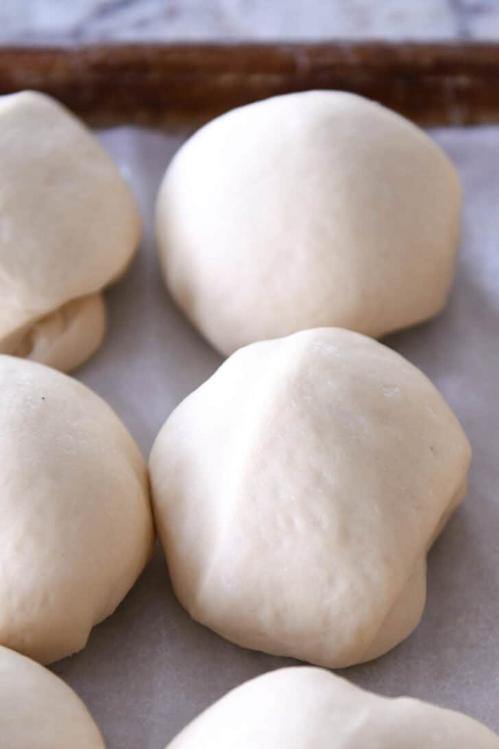 Raw dough balls on a piece of parchment paper.