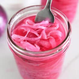 Fork in jar with red onions and vinegar.