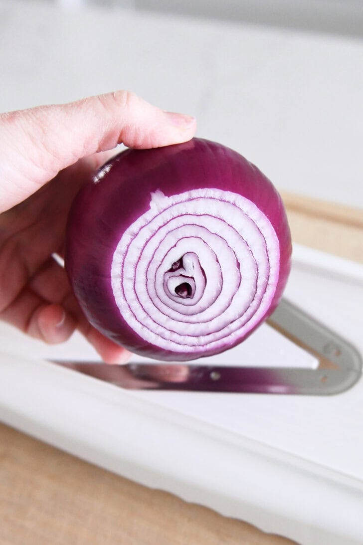 Red onion above mandoline slicer.