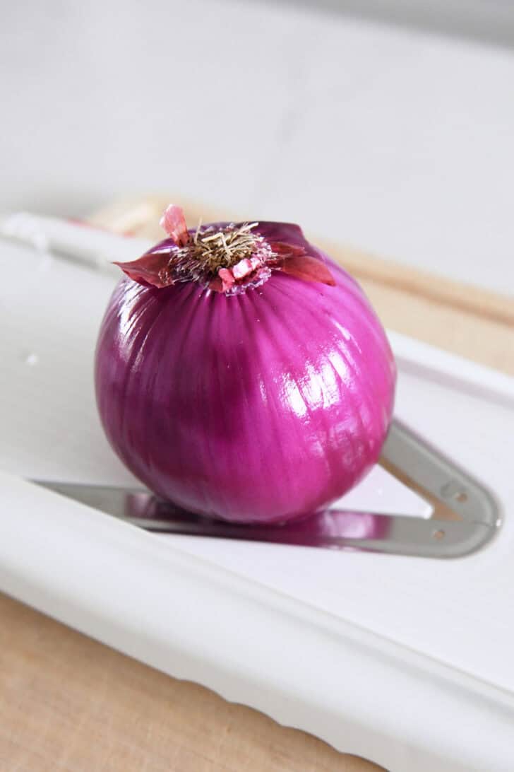 Red onion on mandoline slicer.